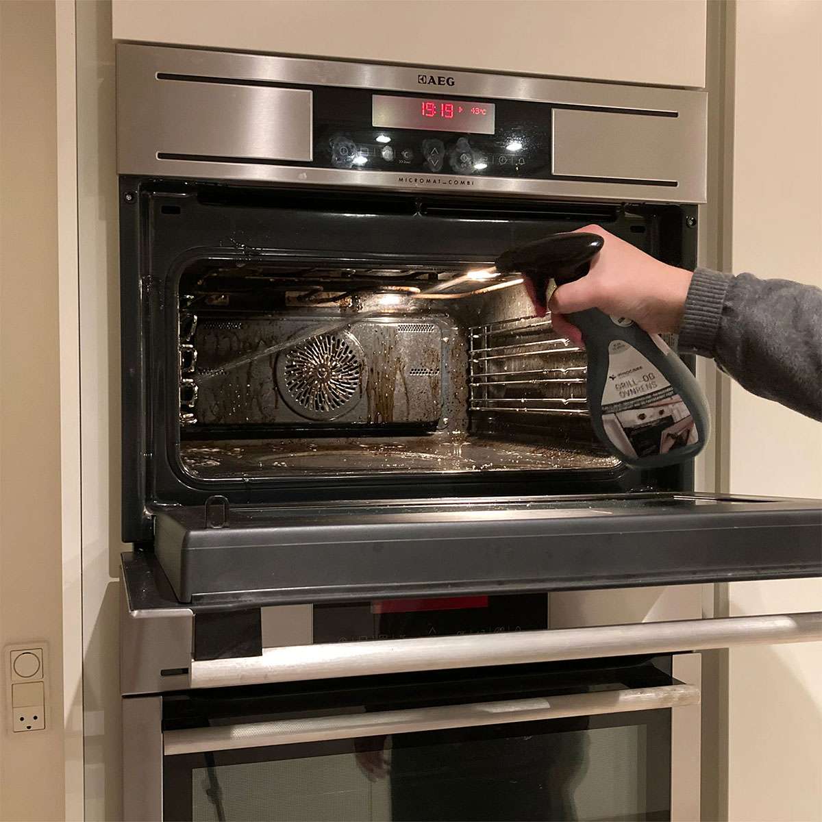 Person sprayer ovnrens i åben indbygningsovn