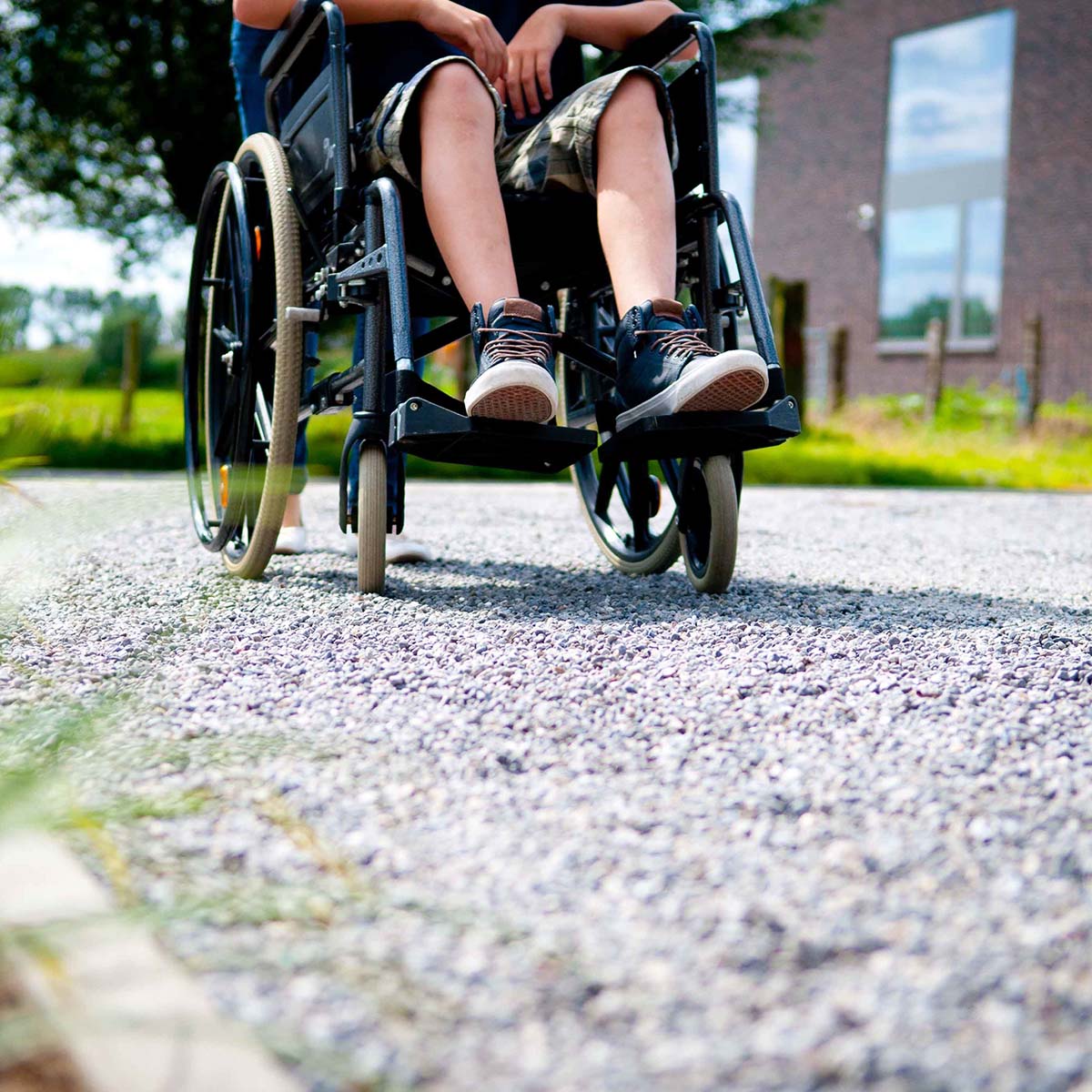 Person i kørestol kører på grussti udenfor
