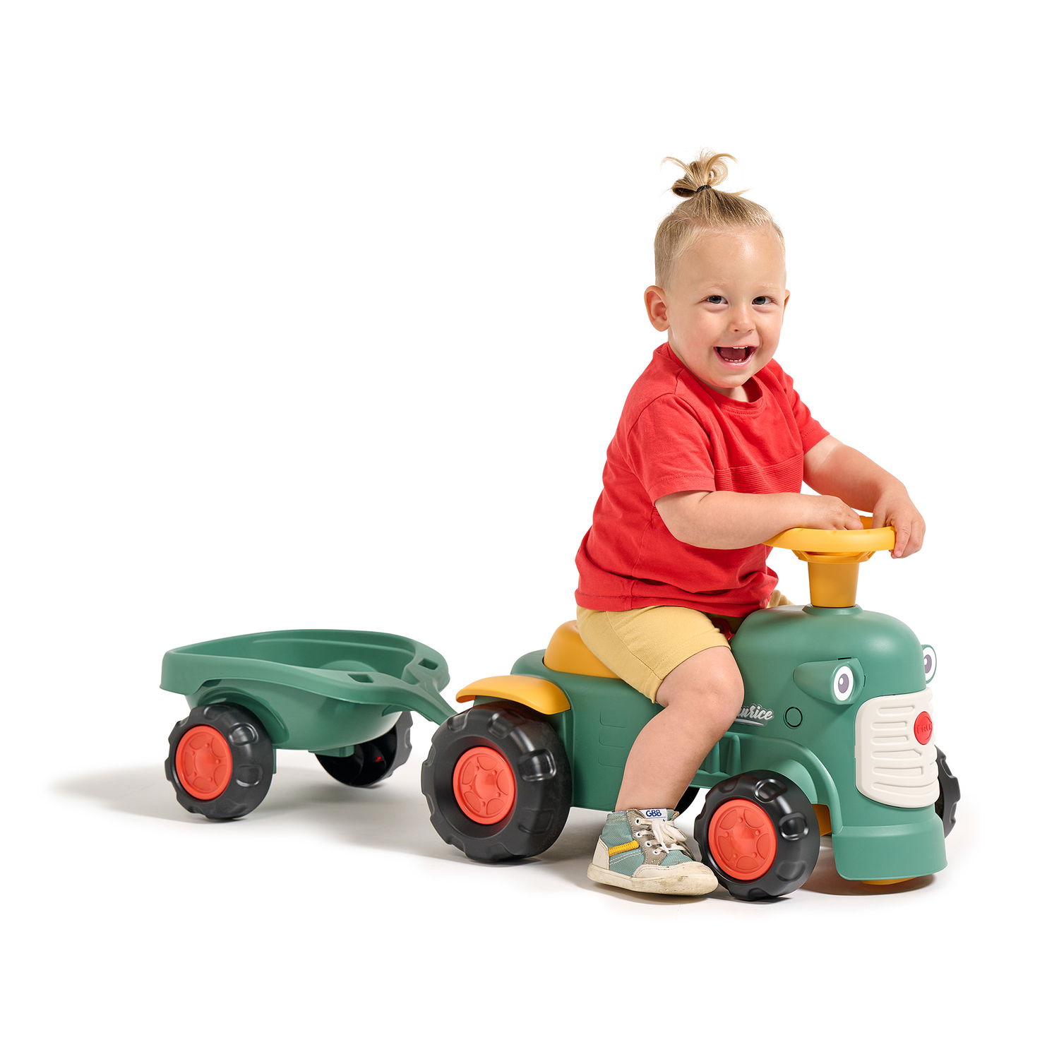 Lille barn leger på grøn ride-on traktor med anhænger