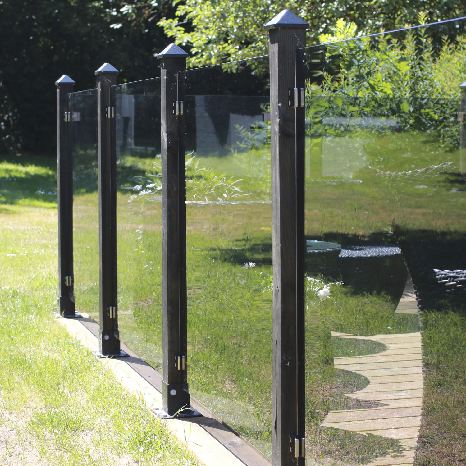 Moderne glashegn med sorte stolper i haven