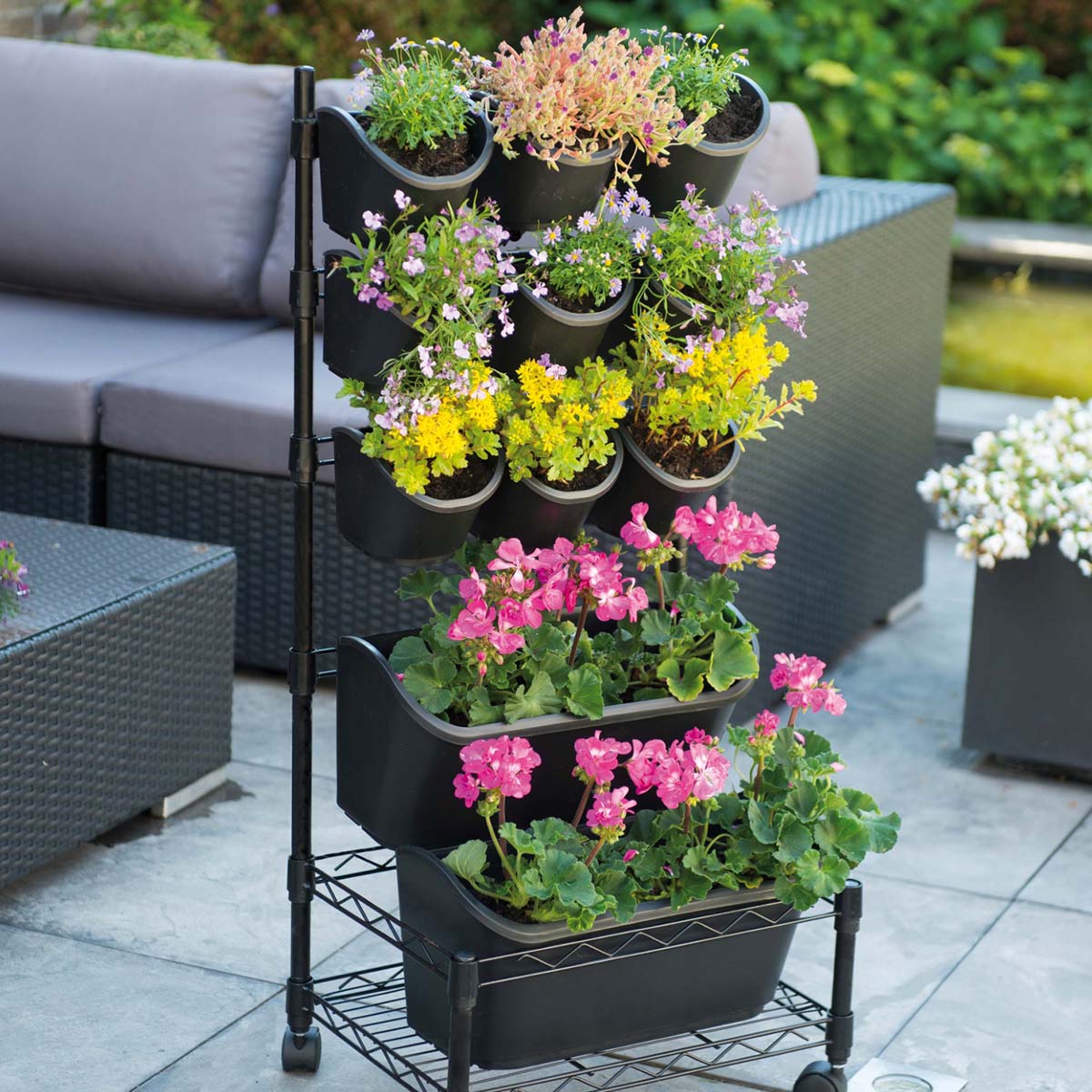 Sort vertikalt plante stativ med blomster på terrasse