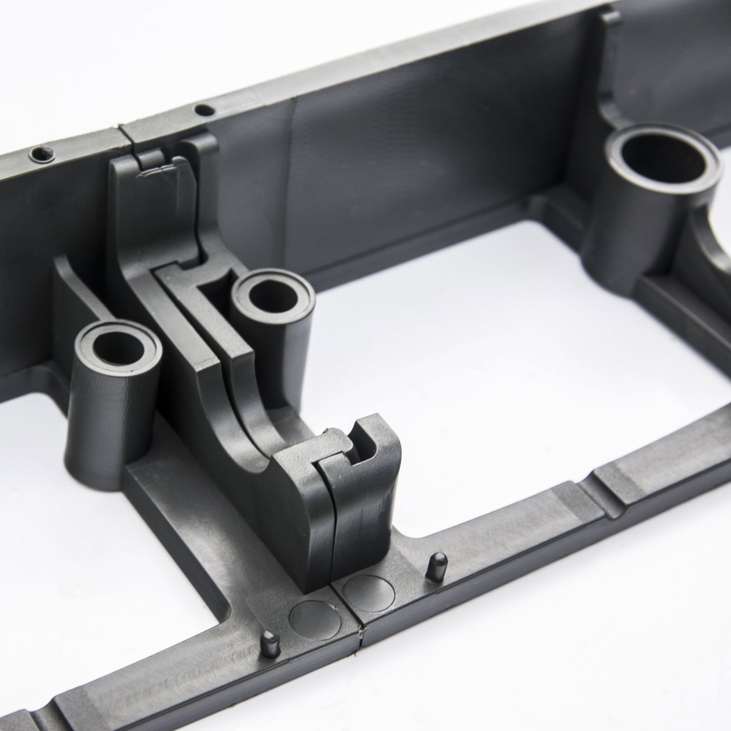 Detalje af sort plastmonteringsdel med huller