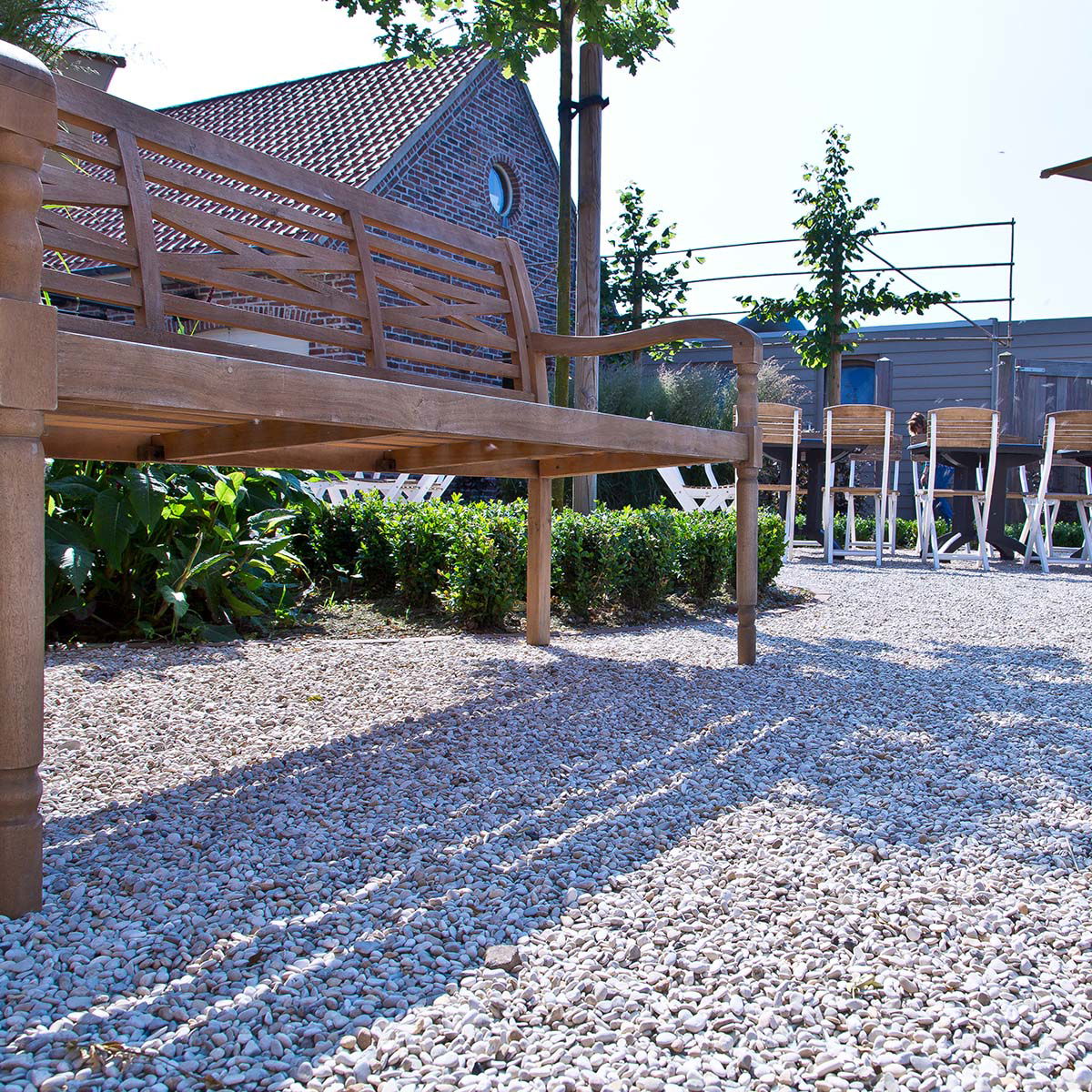 Udendørs træbænk i solrig have på grus