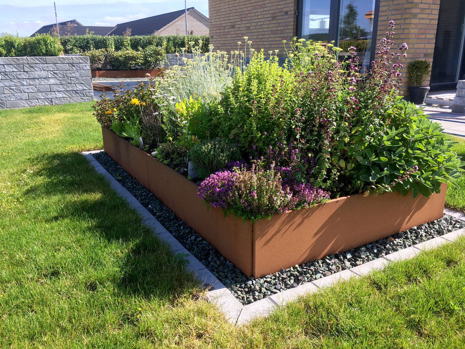 Rektangulært højbed i cortenstål fyldt med blomster