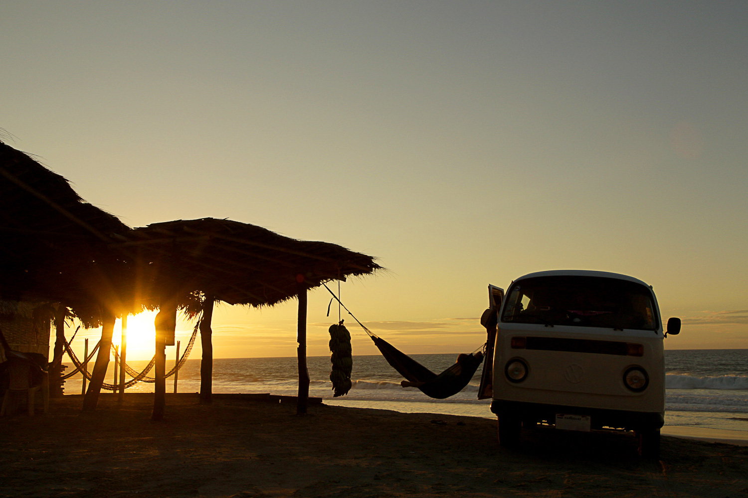 Hængekøje mellem strandhytte og camper ved solnedgang