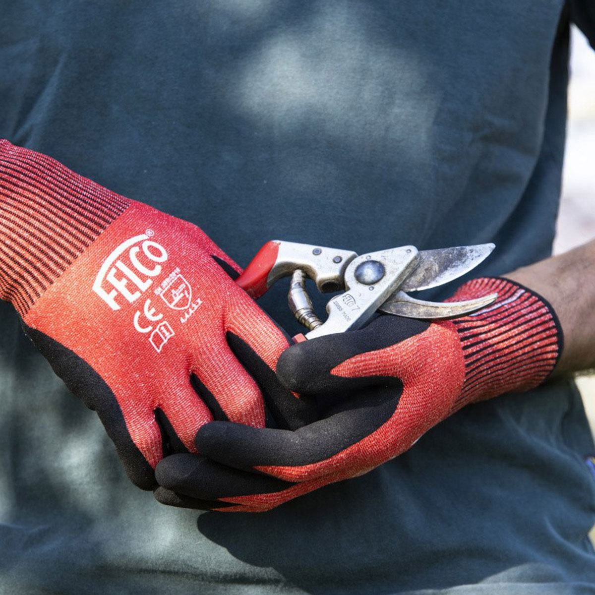 Person med røde FELCO havehandsker og beskæresaks