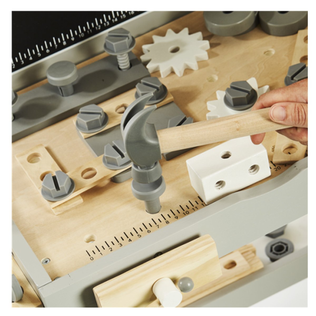 Barn leger med træværktøj og hammer ved værkstedsbord