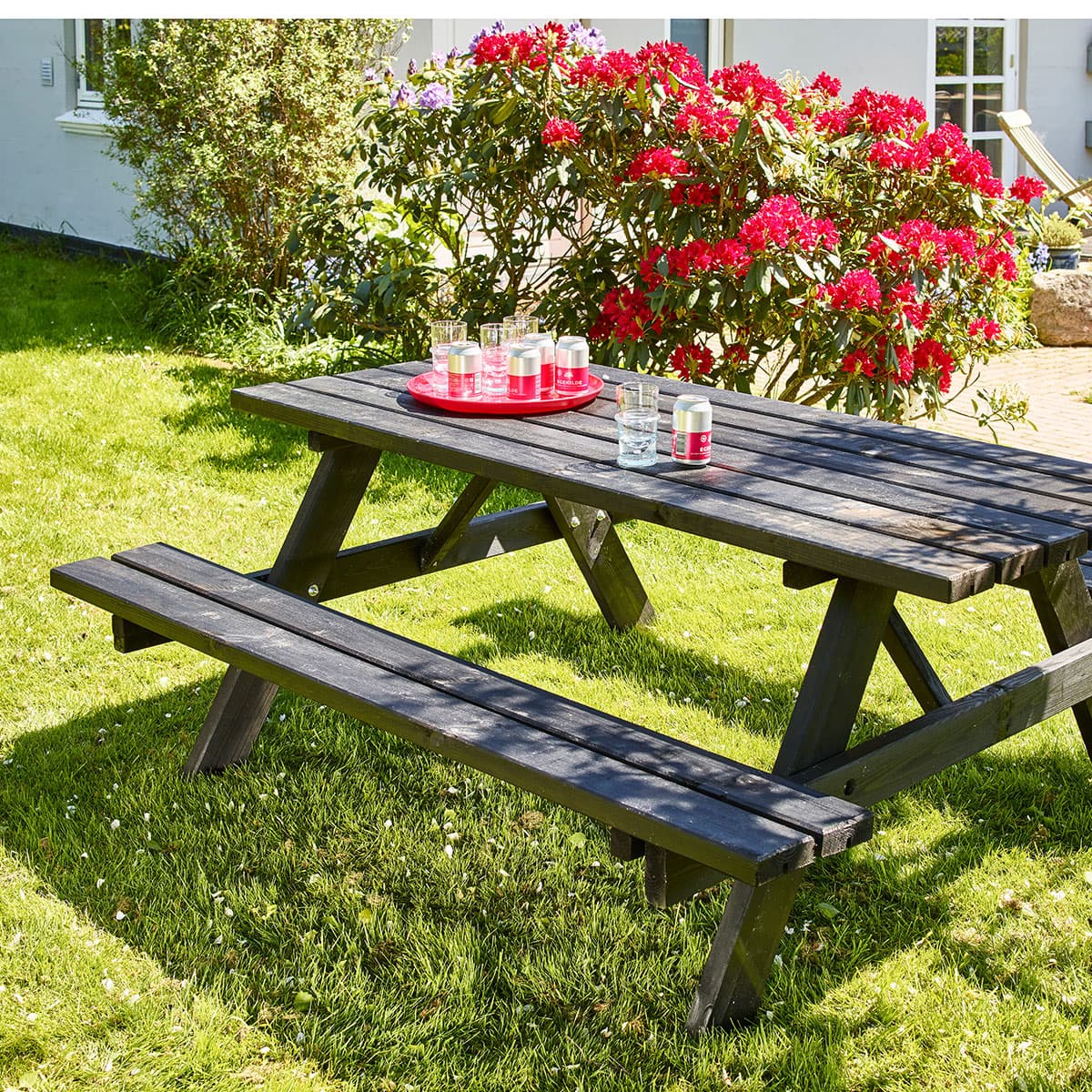 Sort træ-picnickbord i have med blomster