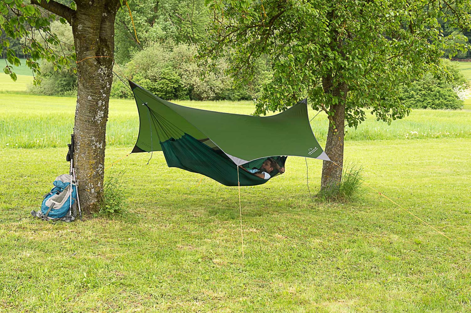 Grøn hængekøje med tarp opsat til camping mellem træer