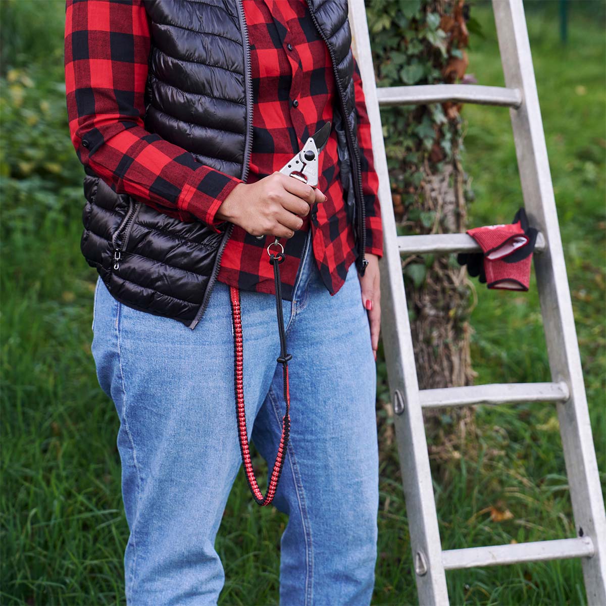 Person holder rødt havebånd med karabinhage ved stige