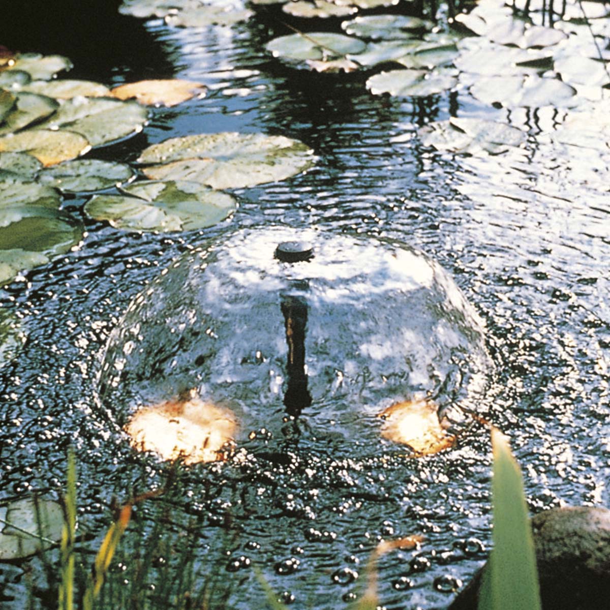 Rund springvandskuppel i havedam med lys