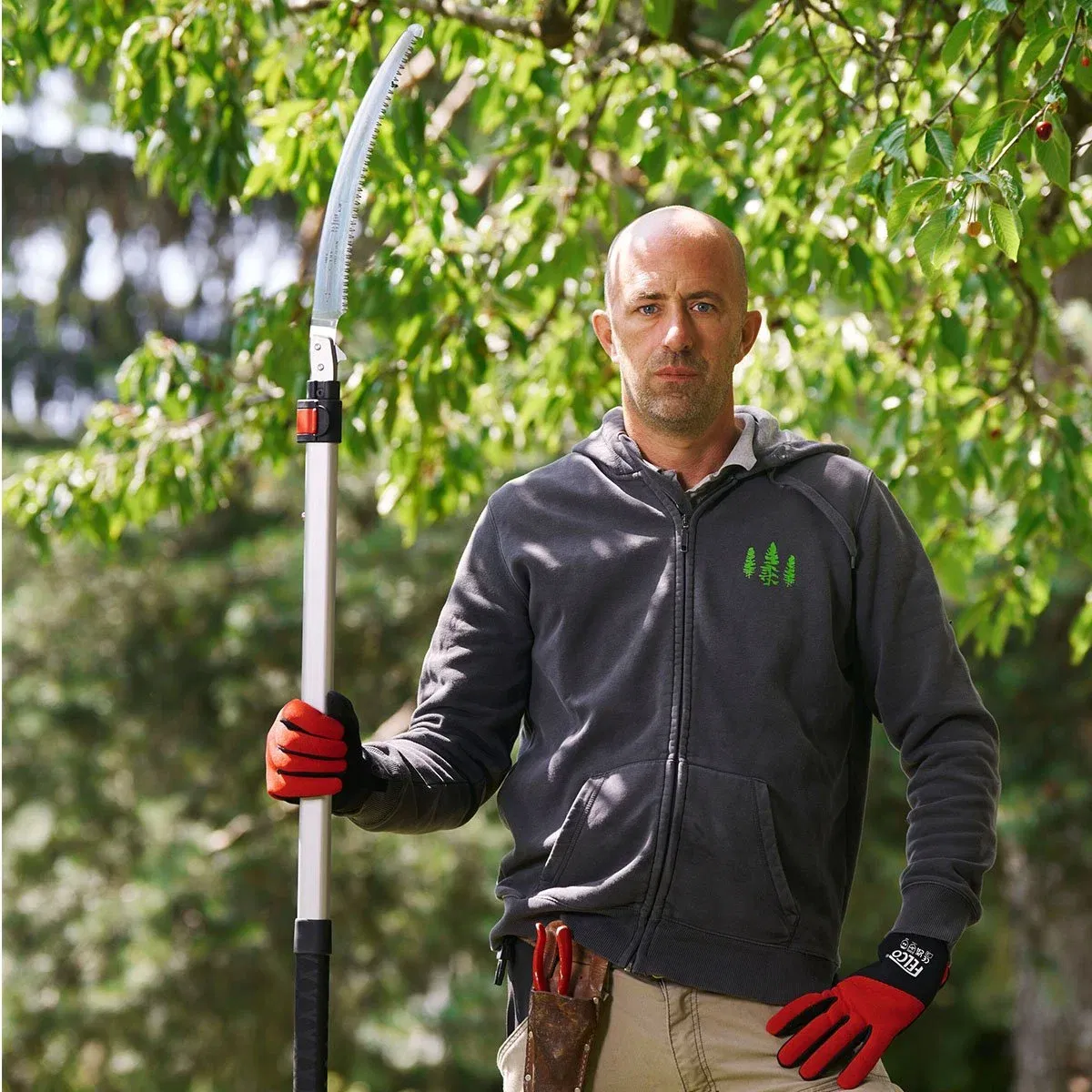Mand bruger stangsav til beskæring af træer