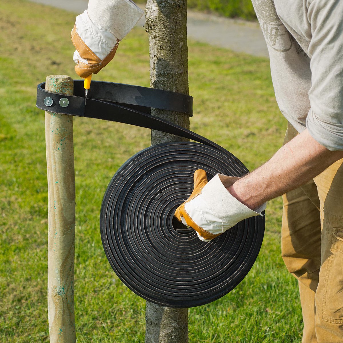 Havearbejder monterer træbindingsbånd på pæl