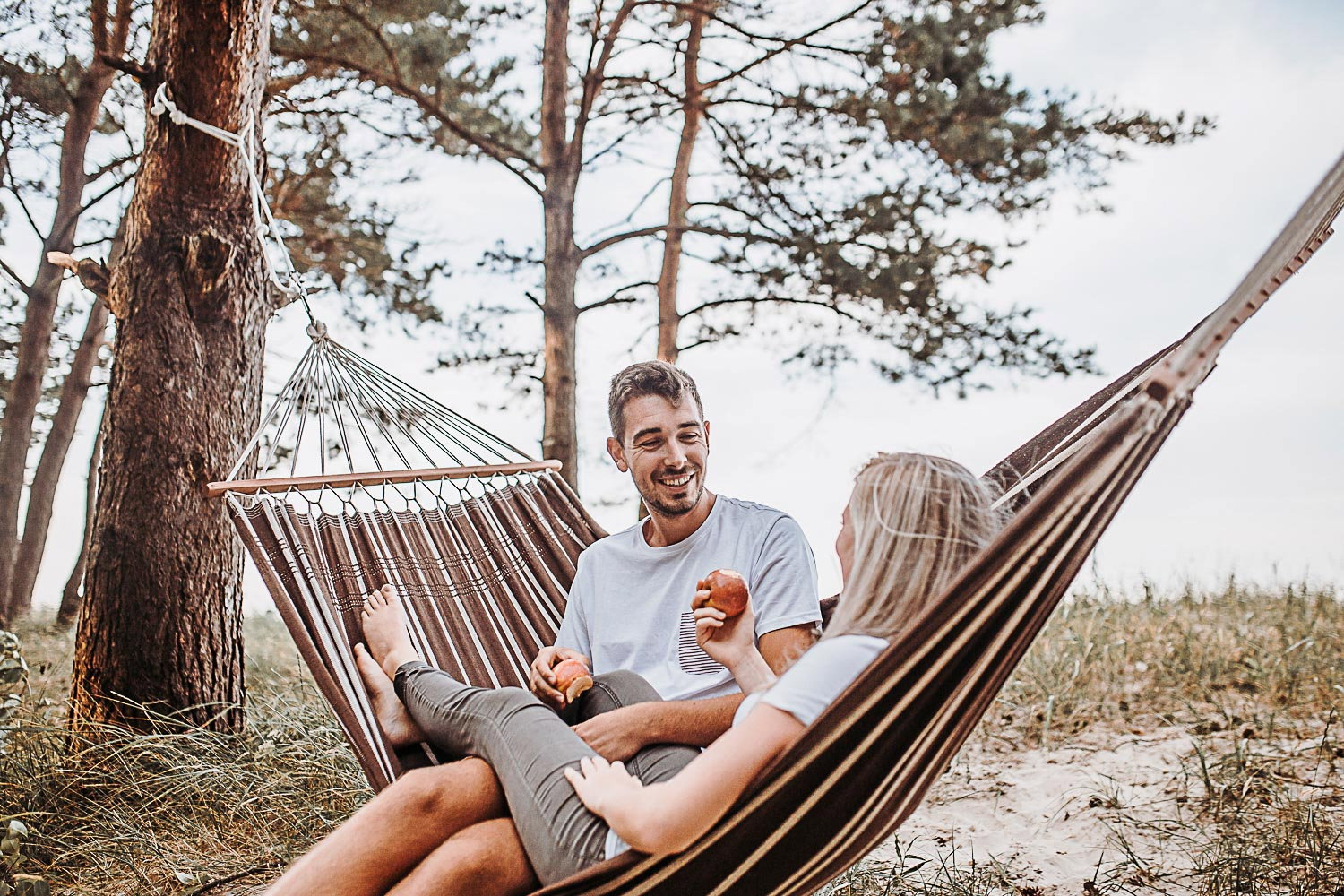 Smilende par slapper af i hængekøje i skoven