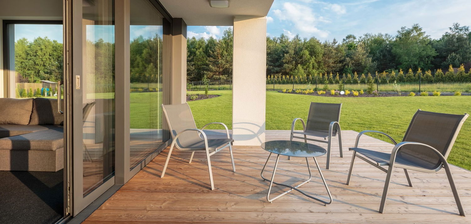 Udendørs cafébord og stole på solrig træterrasse