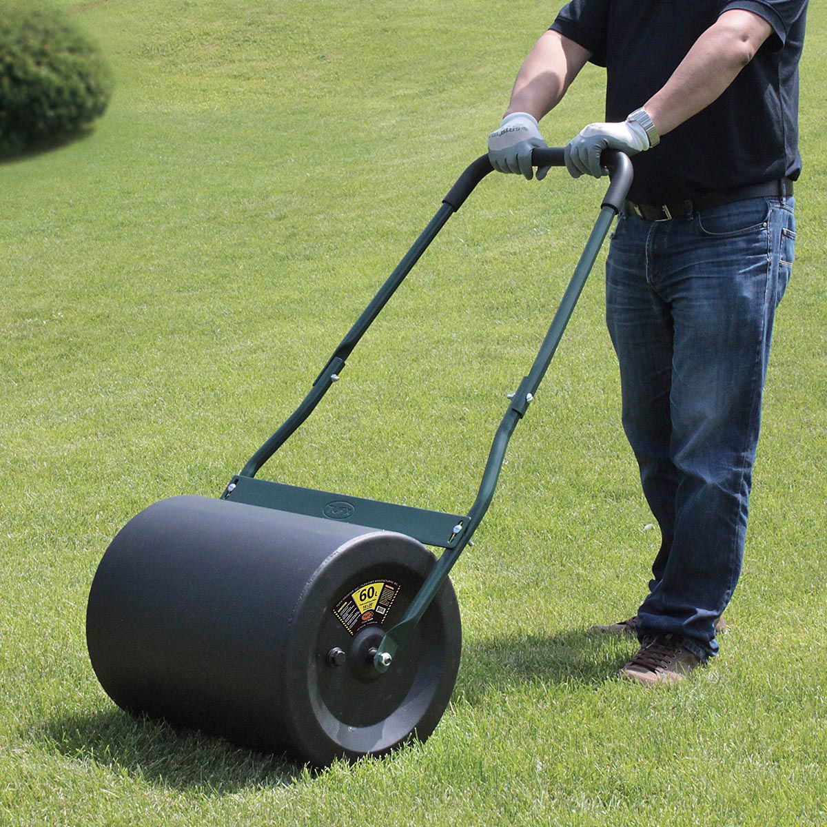 Mand bruger hånddrevet plænevalse på græsplæne