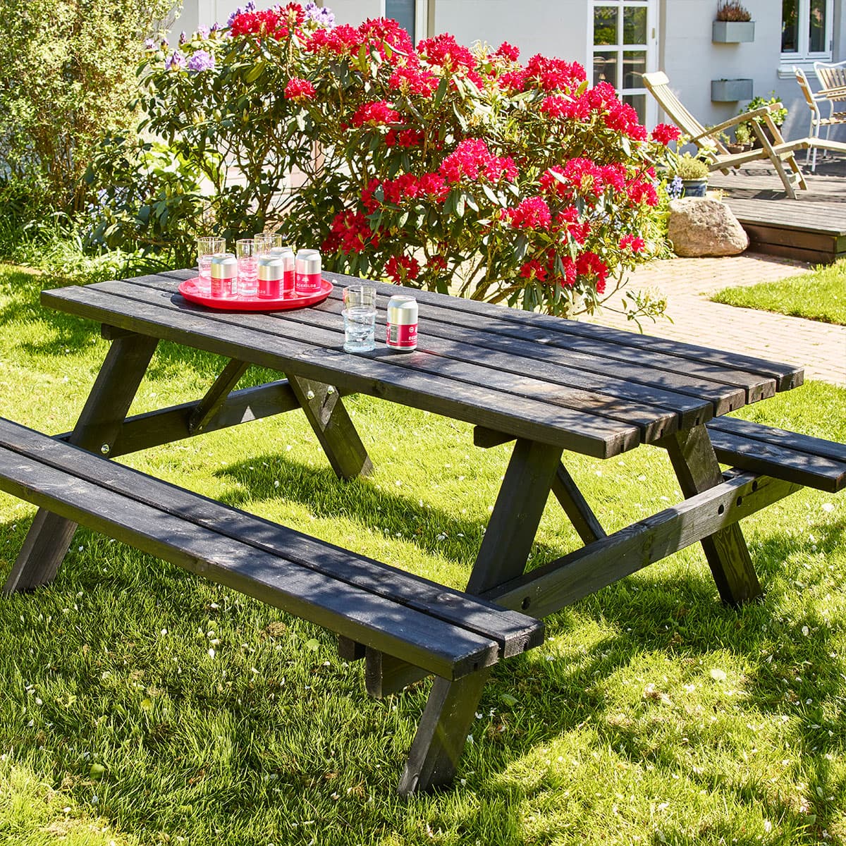 Sort træ-picnicbord i solrig have