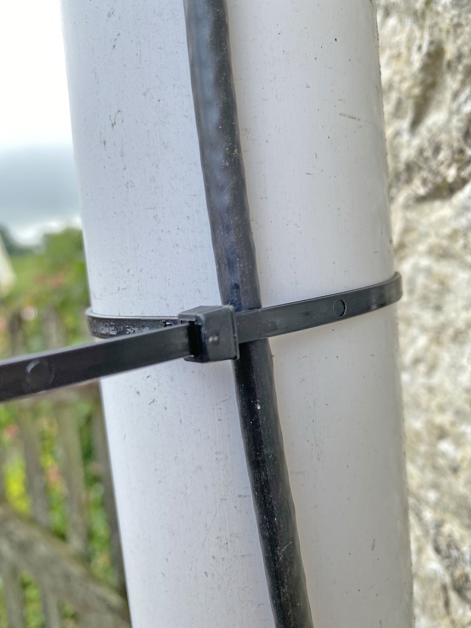 Sort strips, der fastgør kabel til rund hvid stolpe