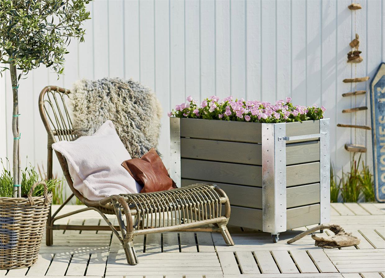 Terrasse med loungestol og stor plantekasse med blomster