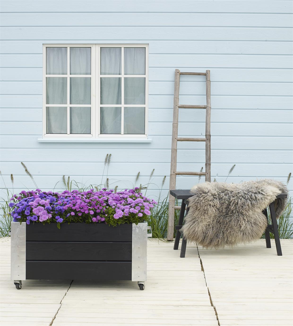 Hyggelig terrasse med blomsterkasse Lys terrasse med sorte møbler og lilla blomsterkasse