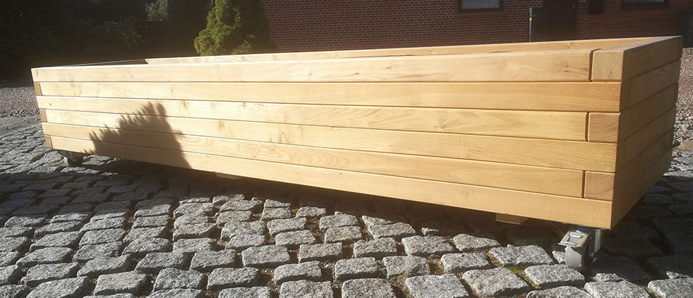 Langt firkantet træhøjbed på hjul på brosten