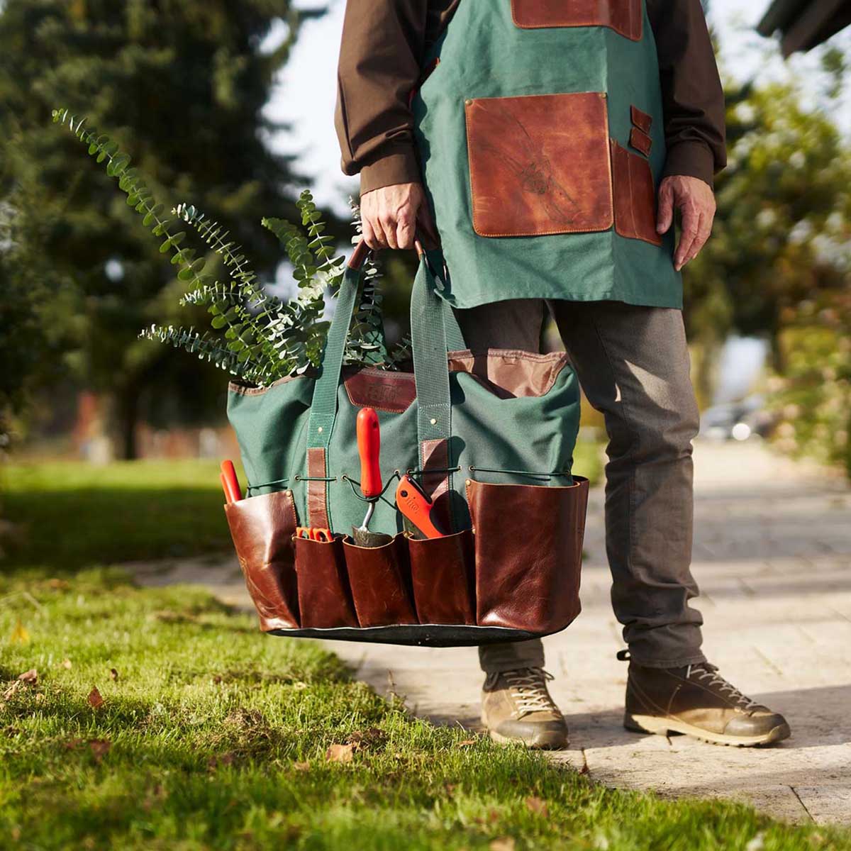 Person bærer grøn og brun haveværktøjstaske