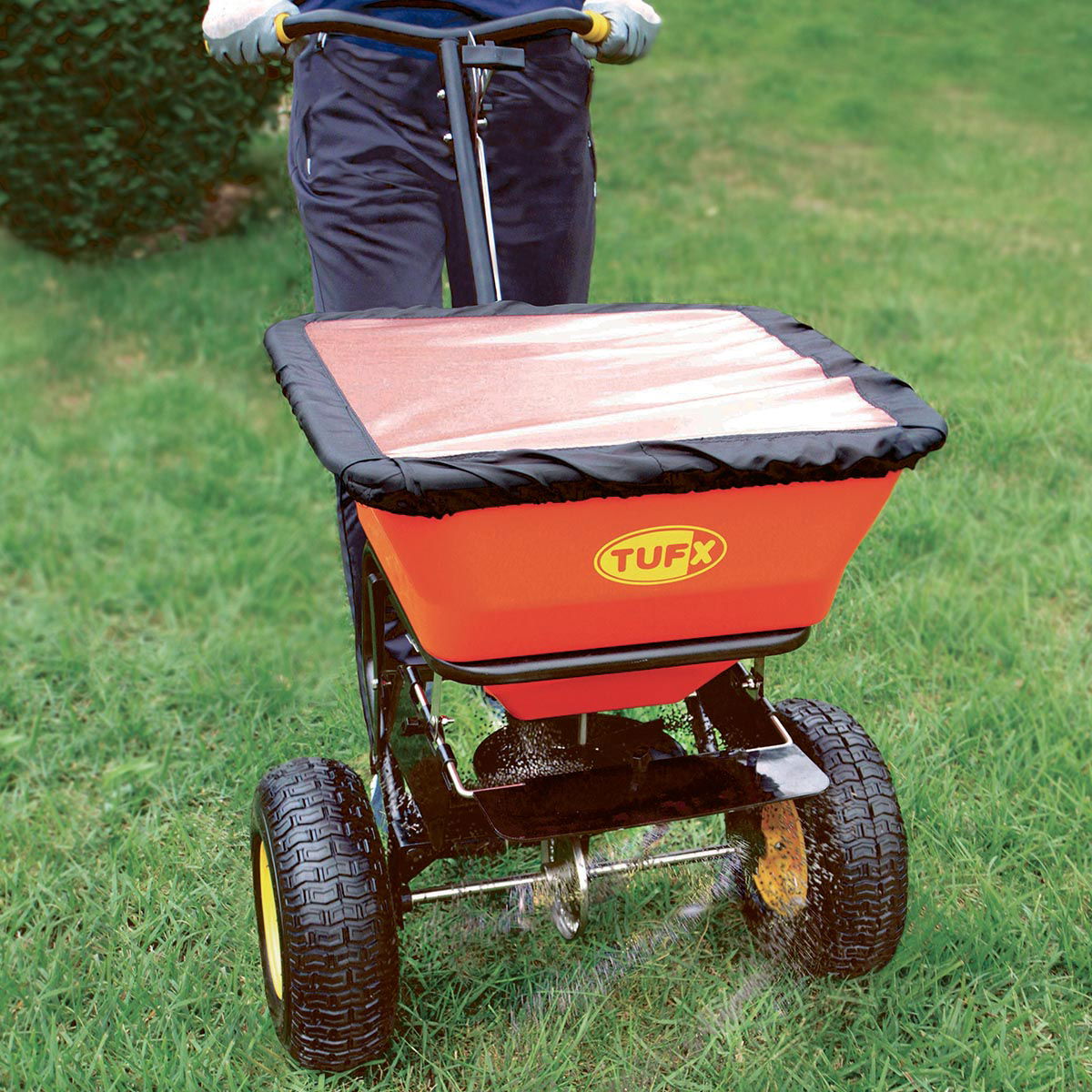 Person bruger Tufx gødningsspreder på græsplæne