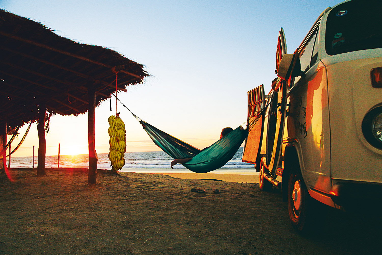 Person slapper af i hængekøje ved strand og campervan