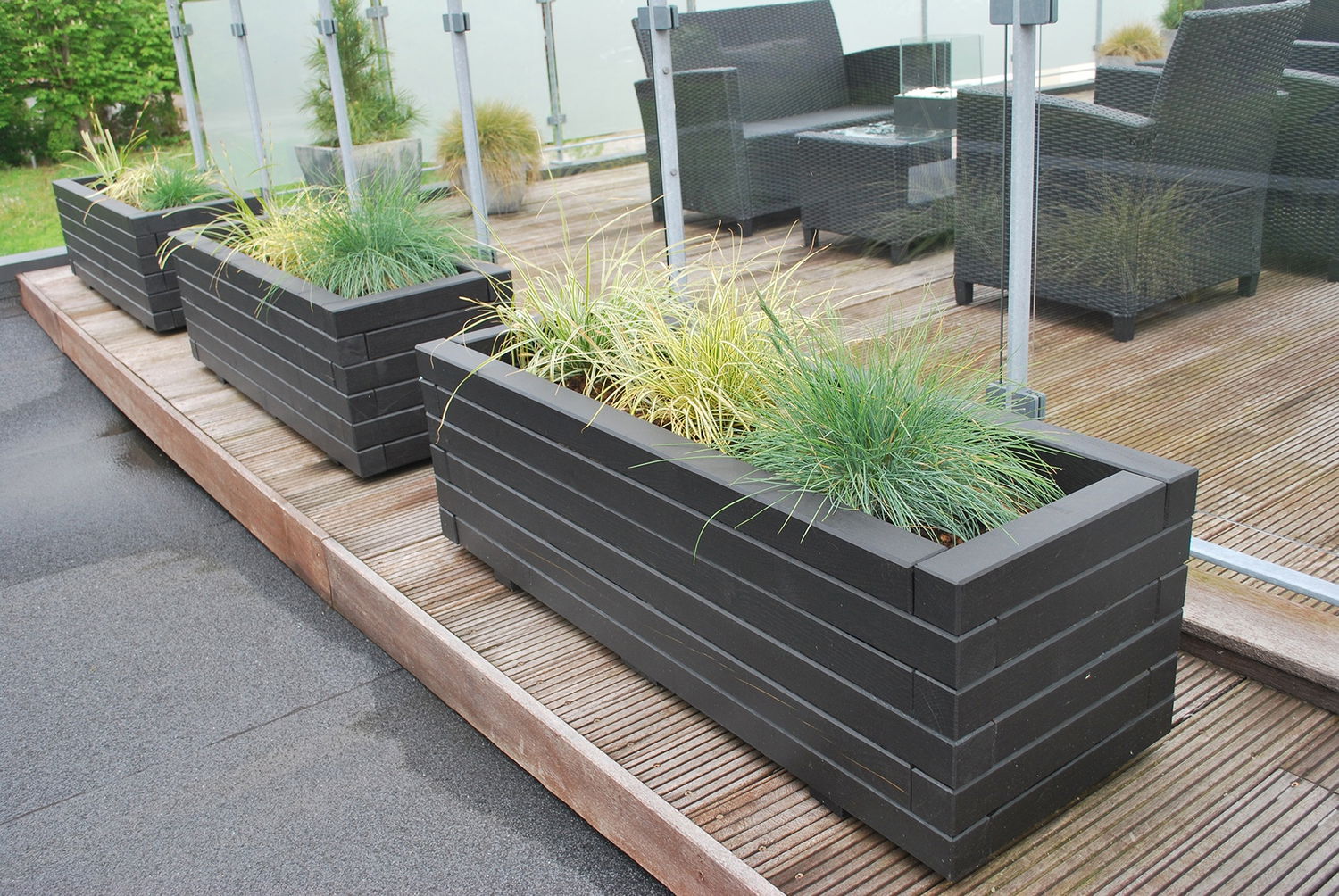 Moderne sorte plantekasser med græs på terrasse