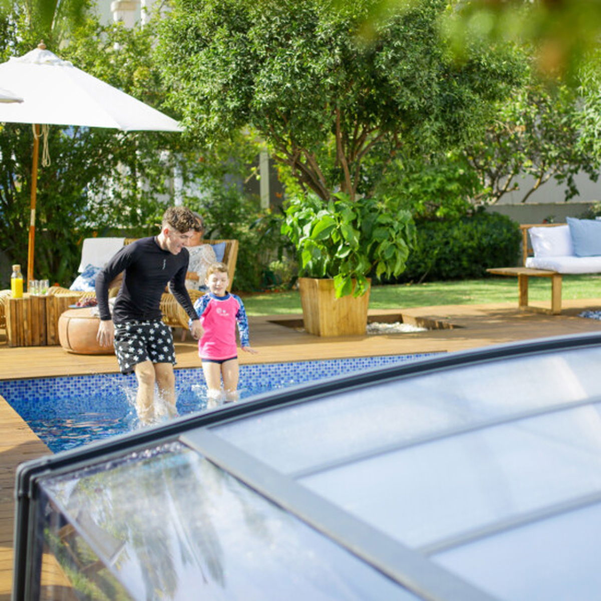Far og barn leger ved overdækket swimmingpool i have