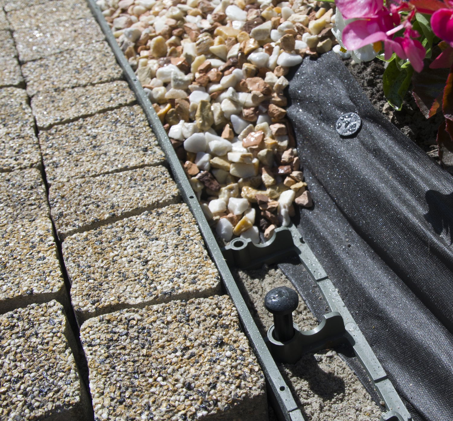 Plastkant mellem belægningssten, dekorsten og geotekstil