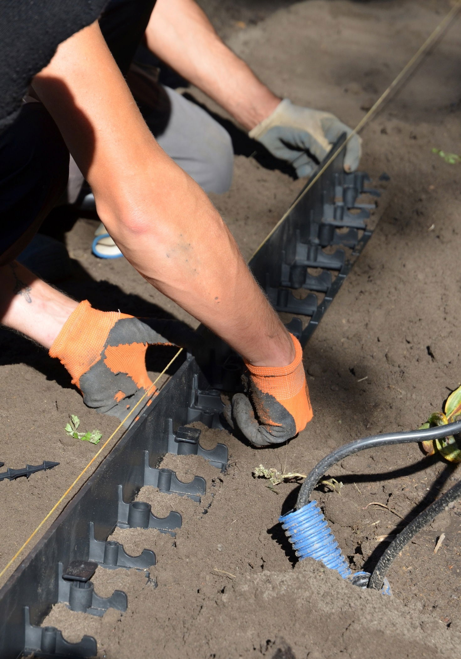 Person monterer plastkant til belægning i haven