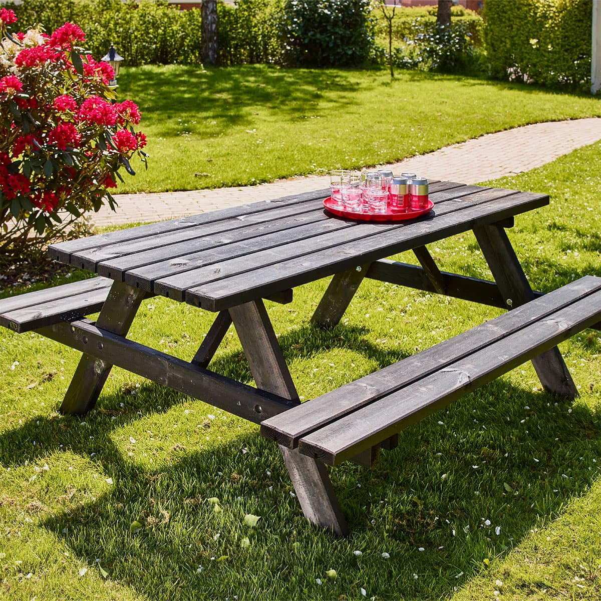 Sort træ-picnicbord med bænk i solrig have