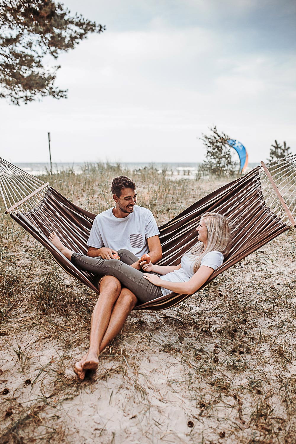 Afslappet par ligger i brun hængekøje på strand