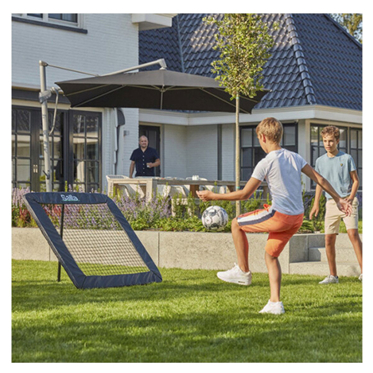 Drenge spiller fodbold med Salta rebounder i haven