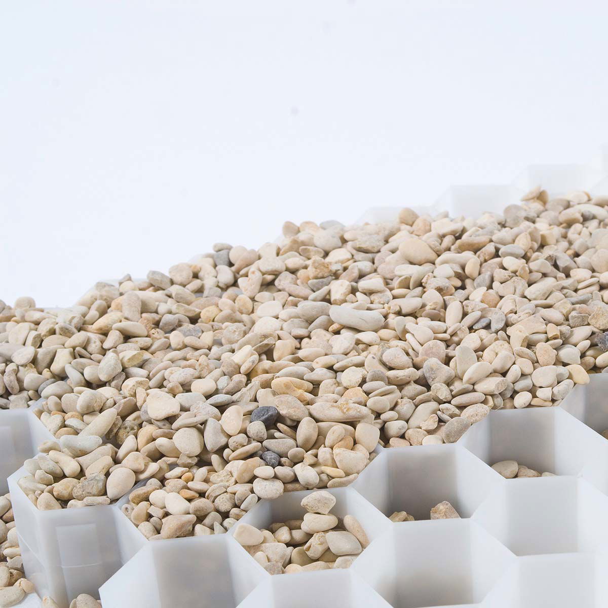 Lyse småsten fylder hvid honeycomb grusmåtte