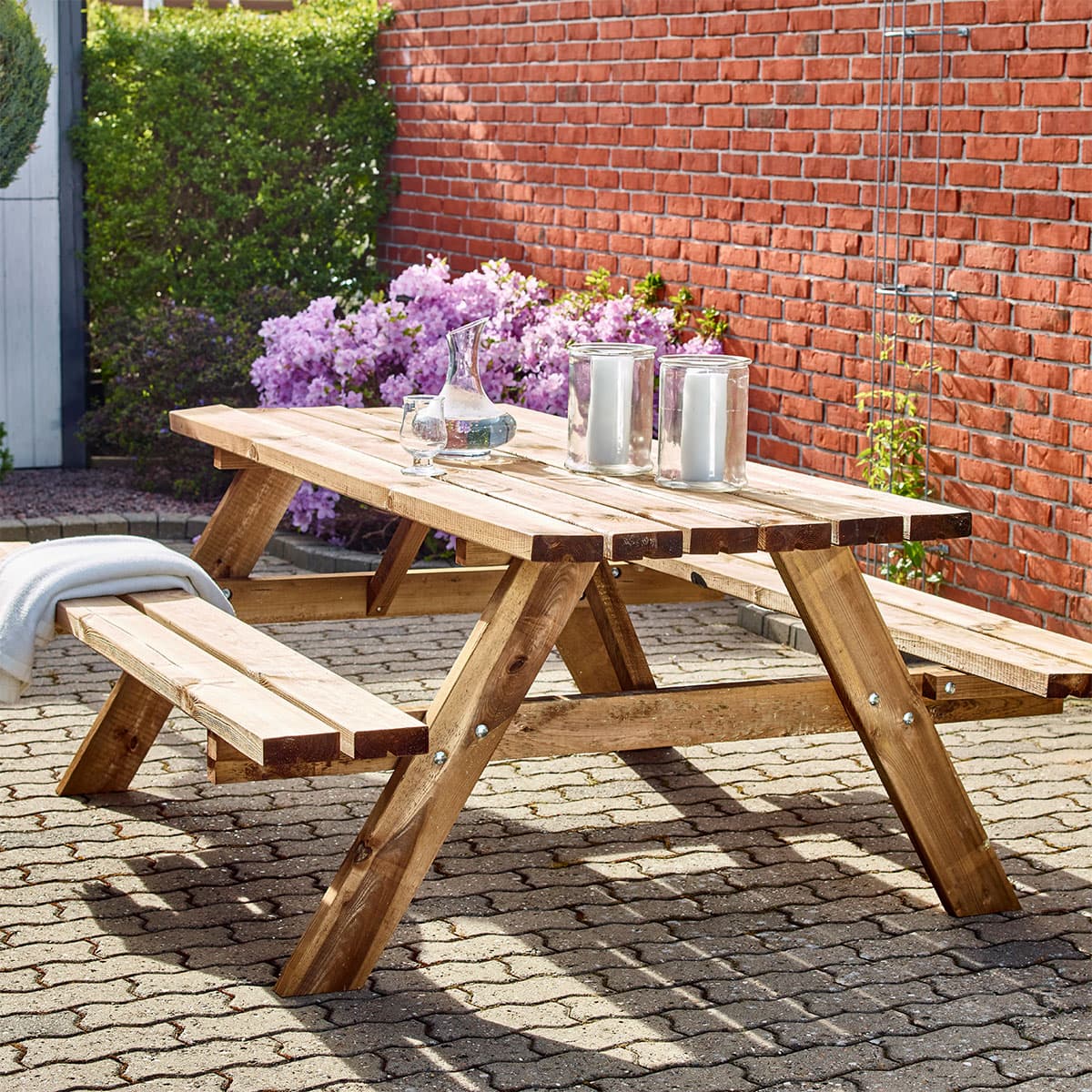 Træ-picnicbord med bænke på solrig terrasse