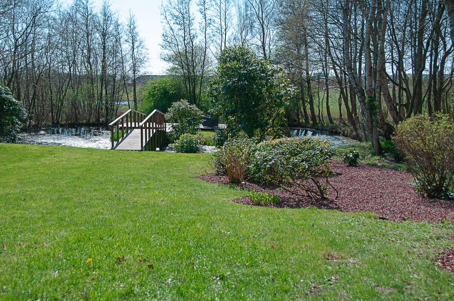 Grøn have med lille træbro over å