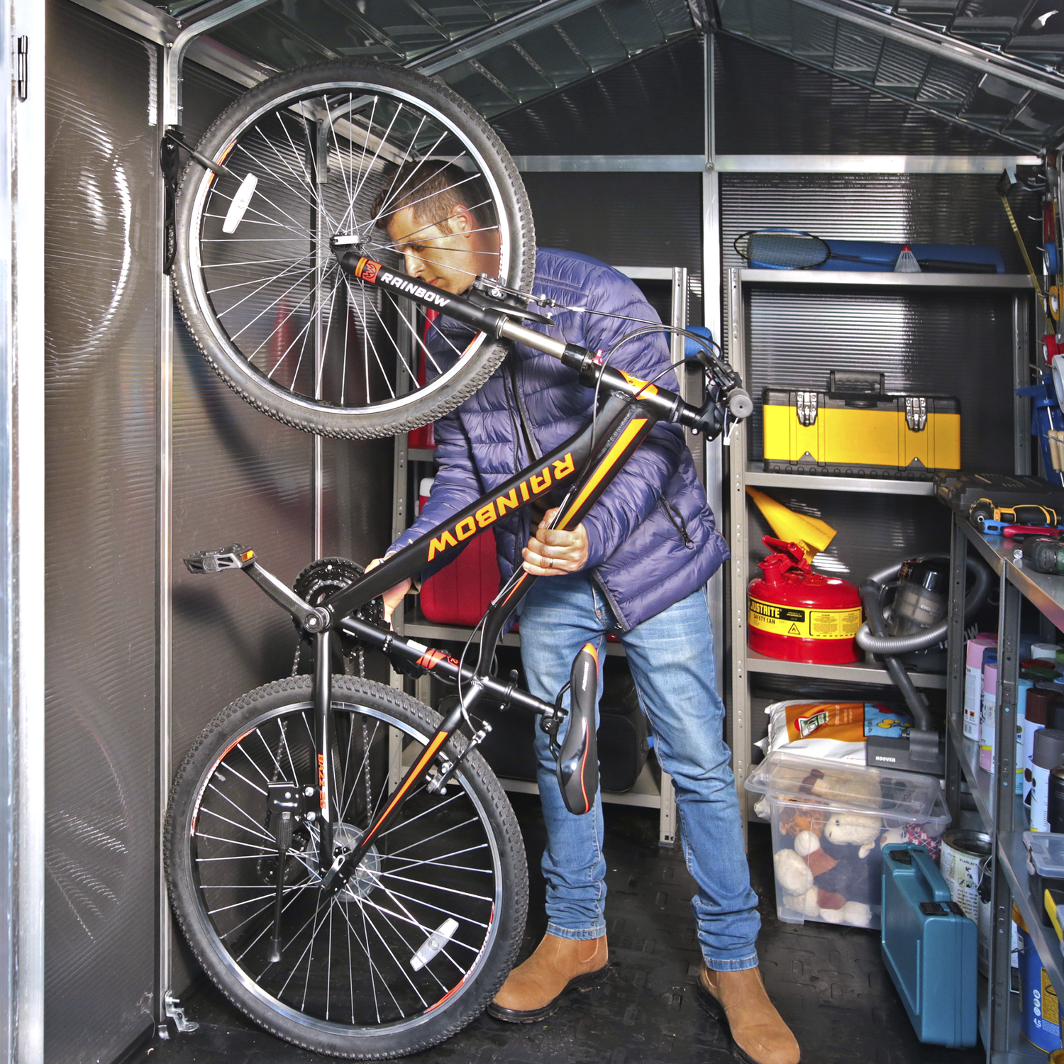 Mand opbevarer cykel i praktisk redskabsskur Mand hænger mountainbike op i metalredskabsskur