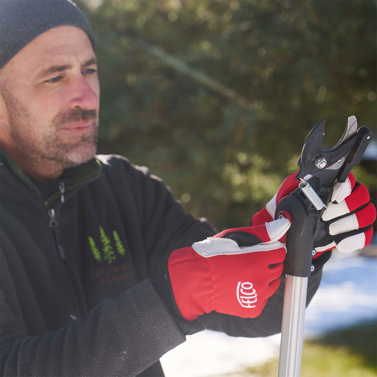 Mand med FELCO handsker justerer beskærersaks på skaft