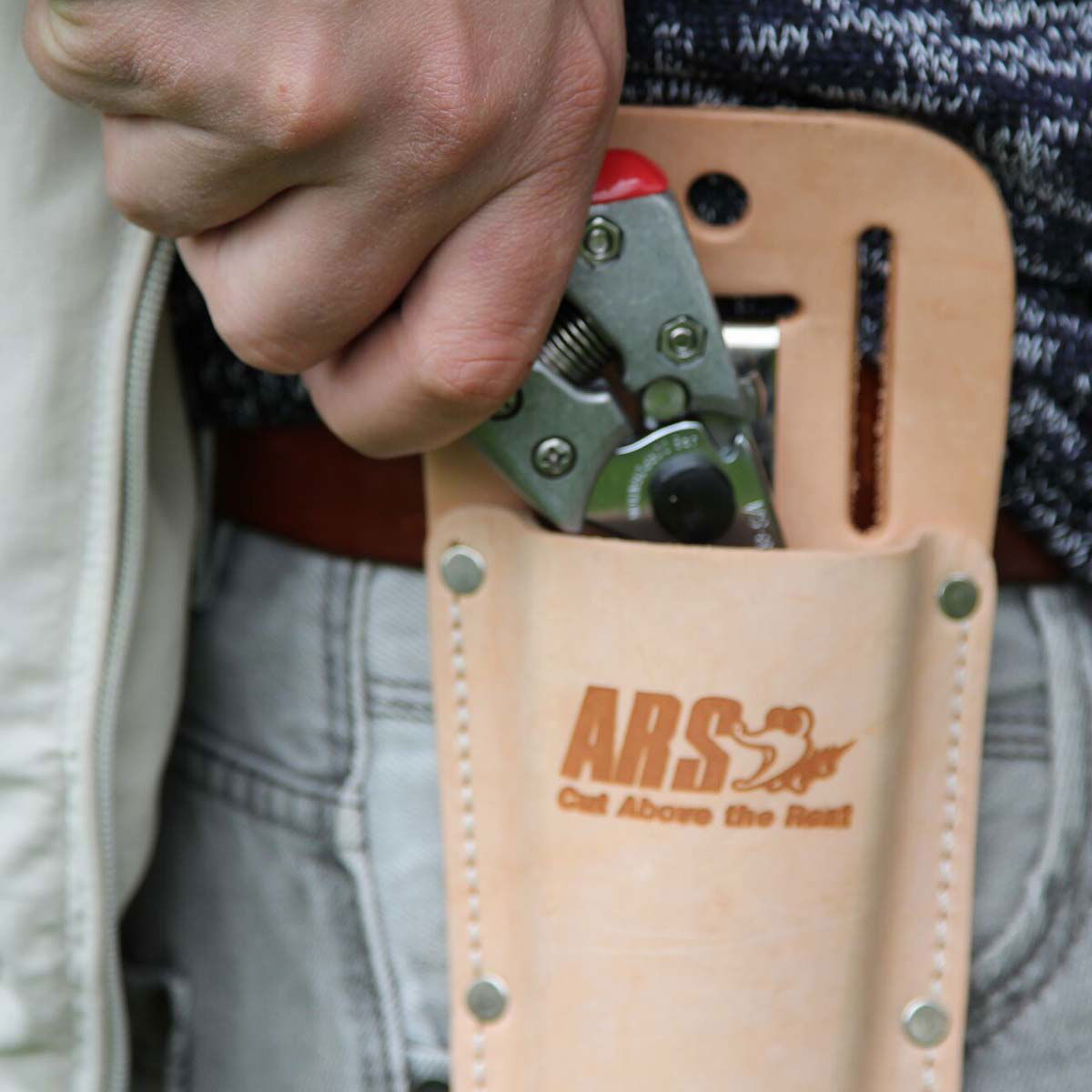 Hånd tager ARS beskæringssaks op af læderhylster