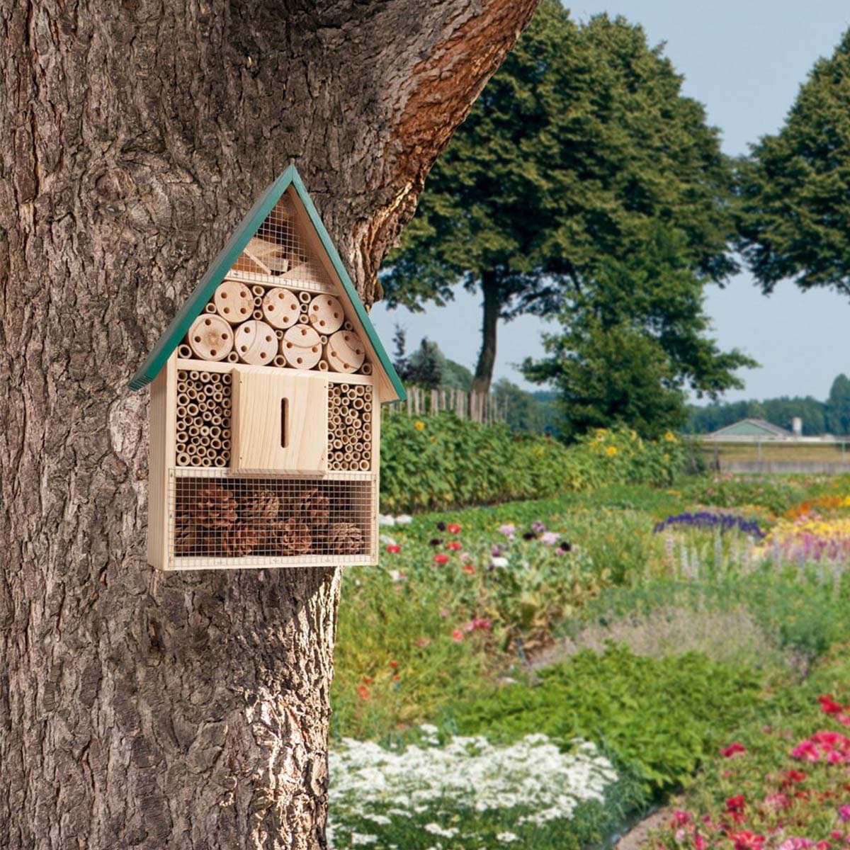 Insektshotel i træ monteret på et træ i haven
