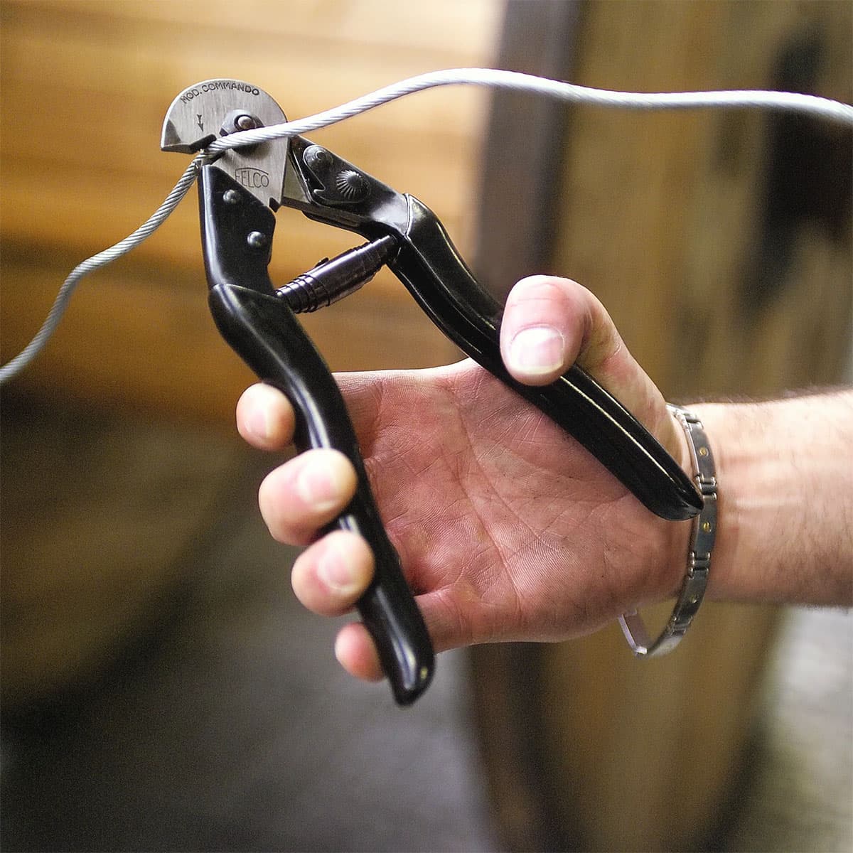 Hånd bruger sort wirecutter til at klippe kabel