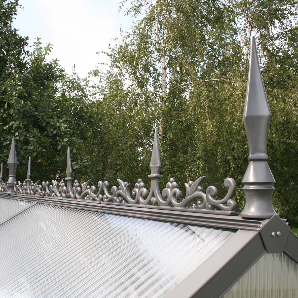 Gråt metal tagkam med spir på drivhus