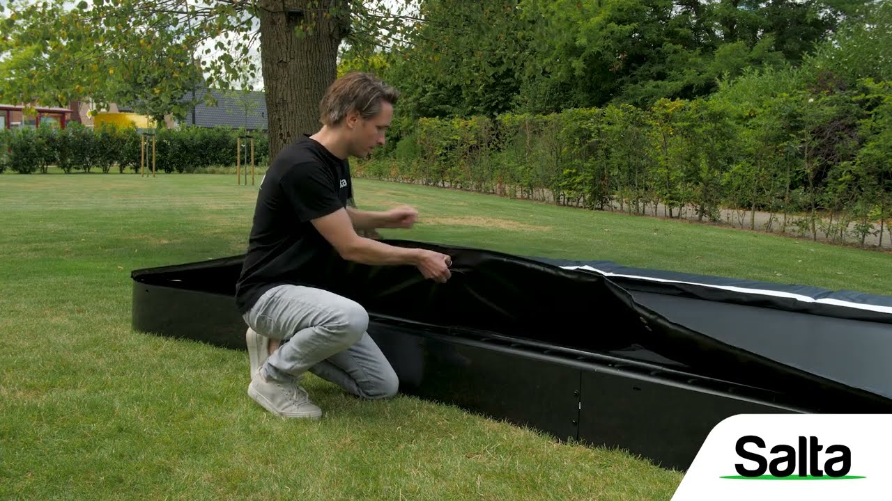 Salta Trampolin Comfort Edition Inground Ø366 cm sort med sikkerhedsnet – Salta Person monterer Salta Trampolin Comfort Edition Inground Ø366 cm i sort i en nedgravet ramme, viser trampsikker kant og opslag til sikkerhedsnet – Salta
